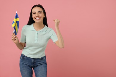 Photo of Happy young woman with flag of Sweden on pink background, space for text
