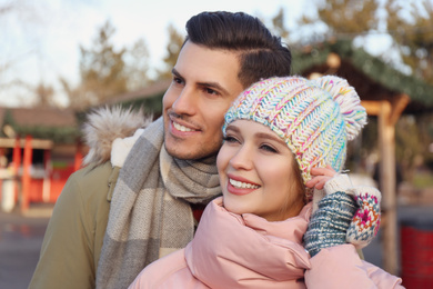 Happy couple in warm clothes at winter fair. Christmas season