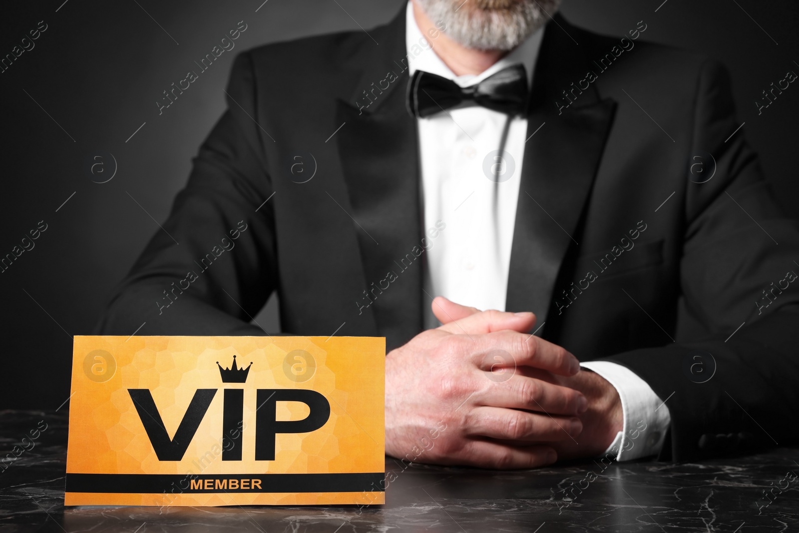 Photo of Man sitting at table with VIP sign on black background, closeup