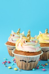 Photo of Cute sweet unicorn cupcakes on light blue background