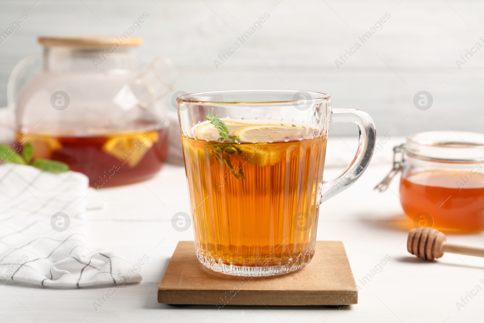 Photo of Hot tea with mint and lemon slices on white table, closeup