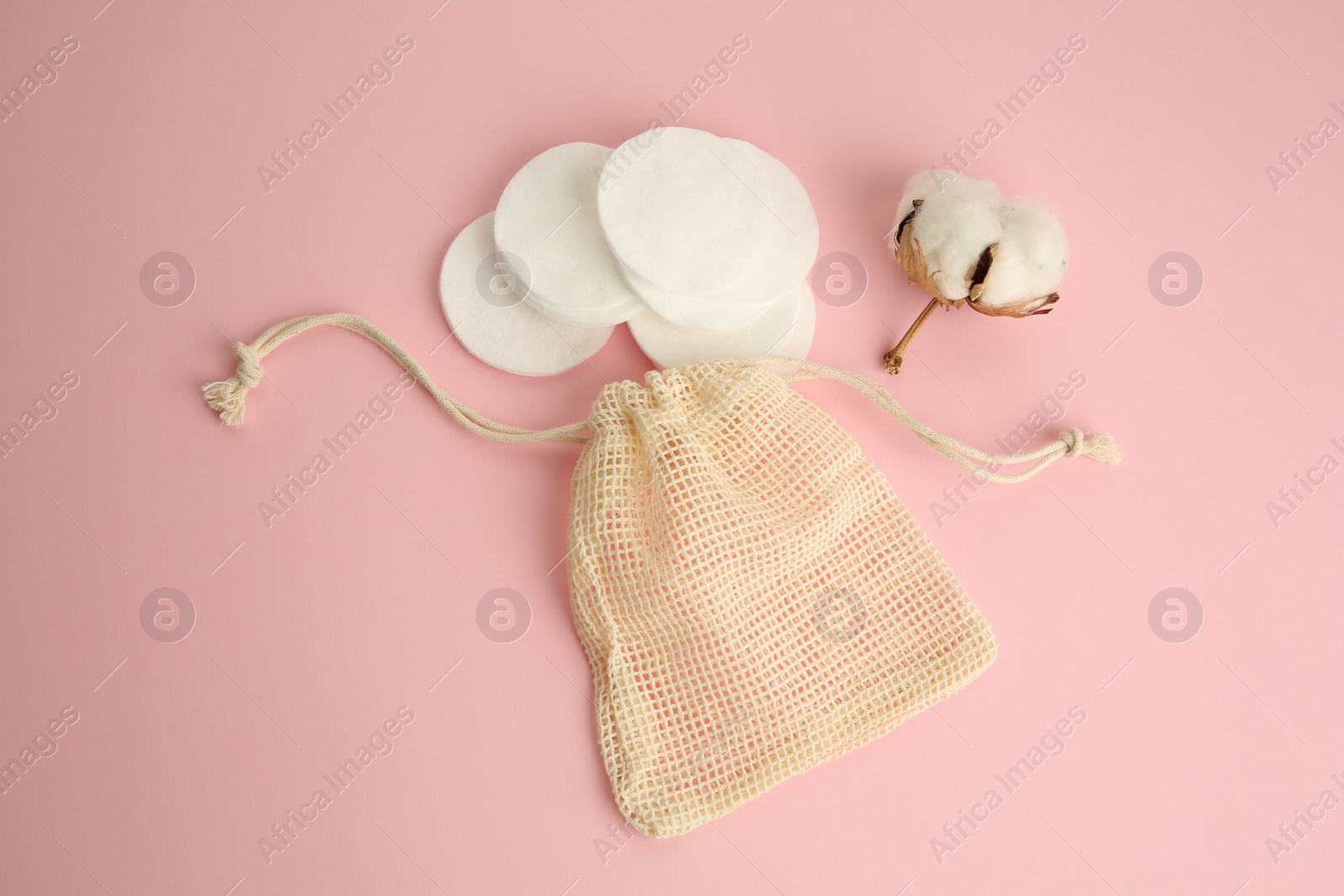 Photo of Bag, cotton pads and flower on pink background, above view