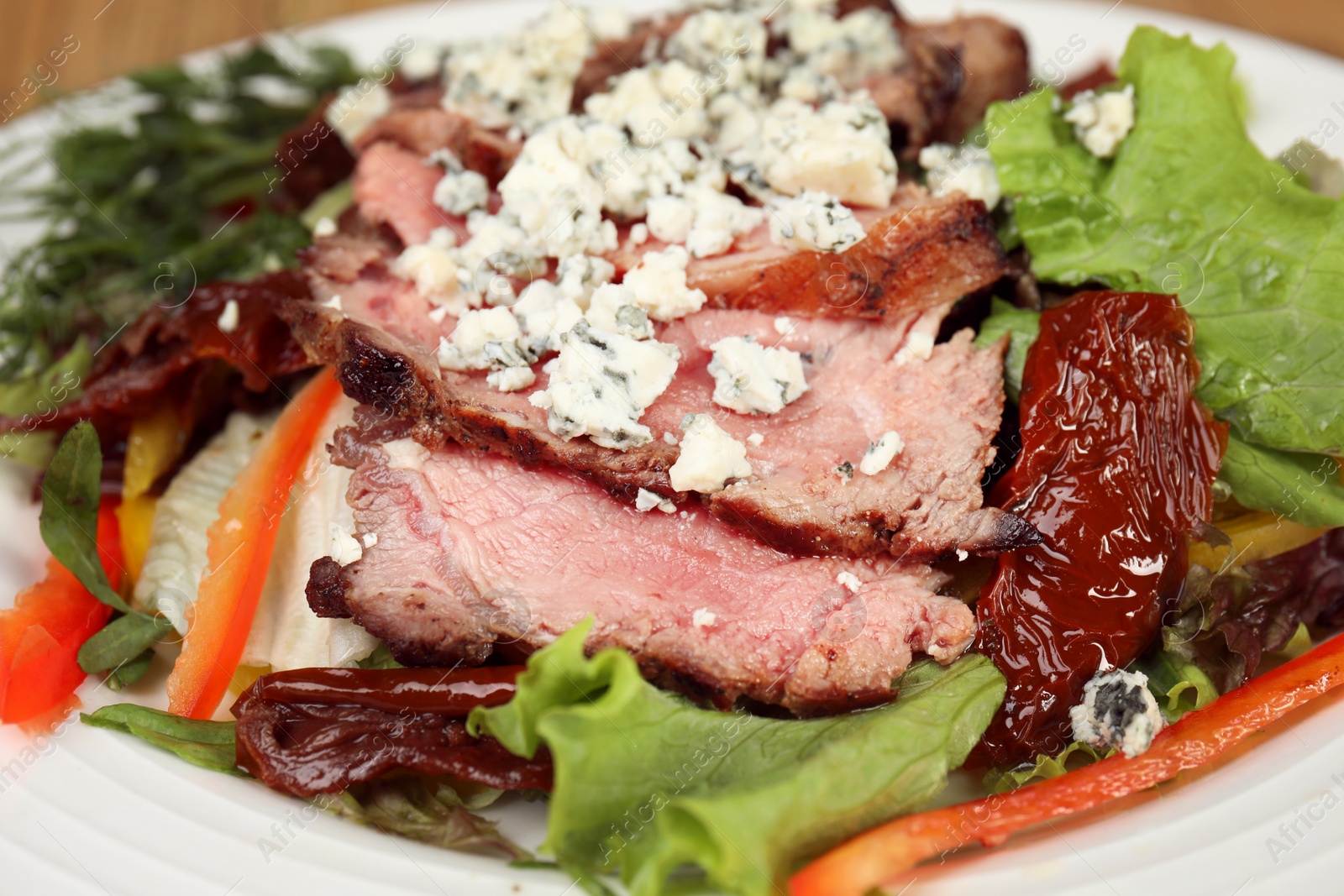 Photo of Delicious salad with roasted meat and vegetables on plate, closeup