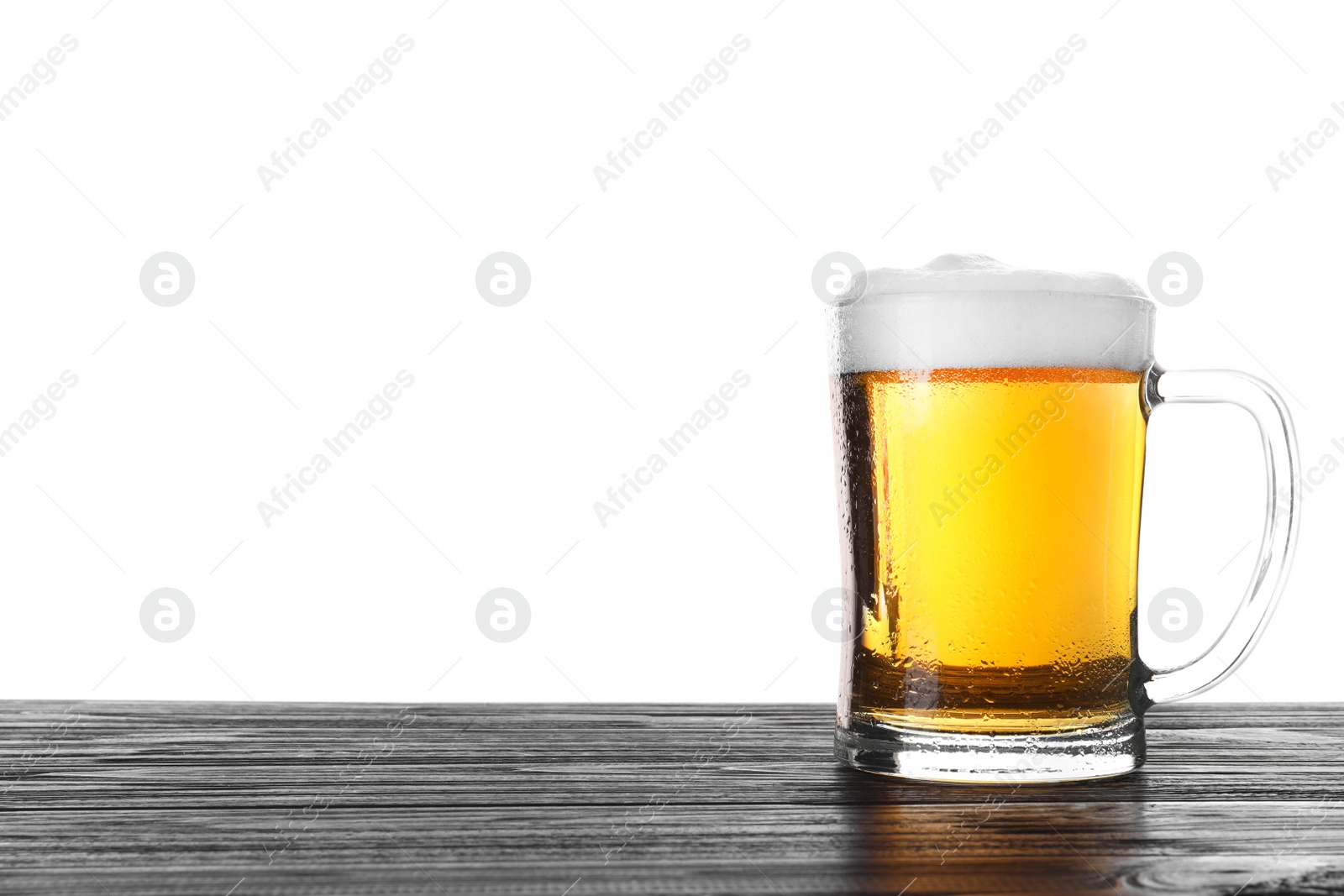 Photo of Glass mug with tasty beer on black wooden table against white background