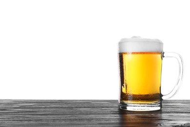 Glass mug with tasty beer on black wooden table against white background