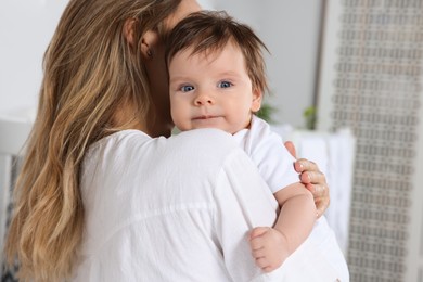 Photo of Mother hugging her cute little baby indoors, closeup