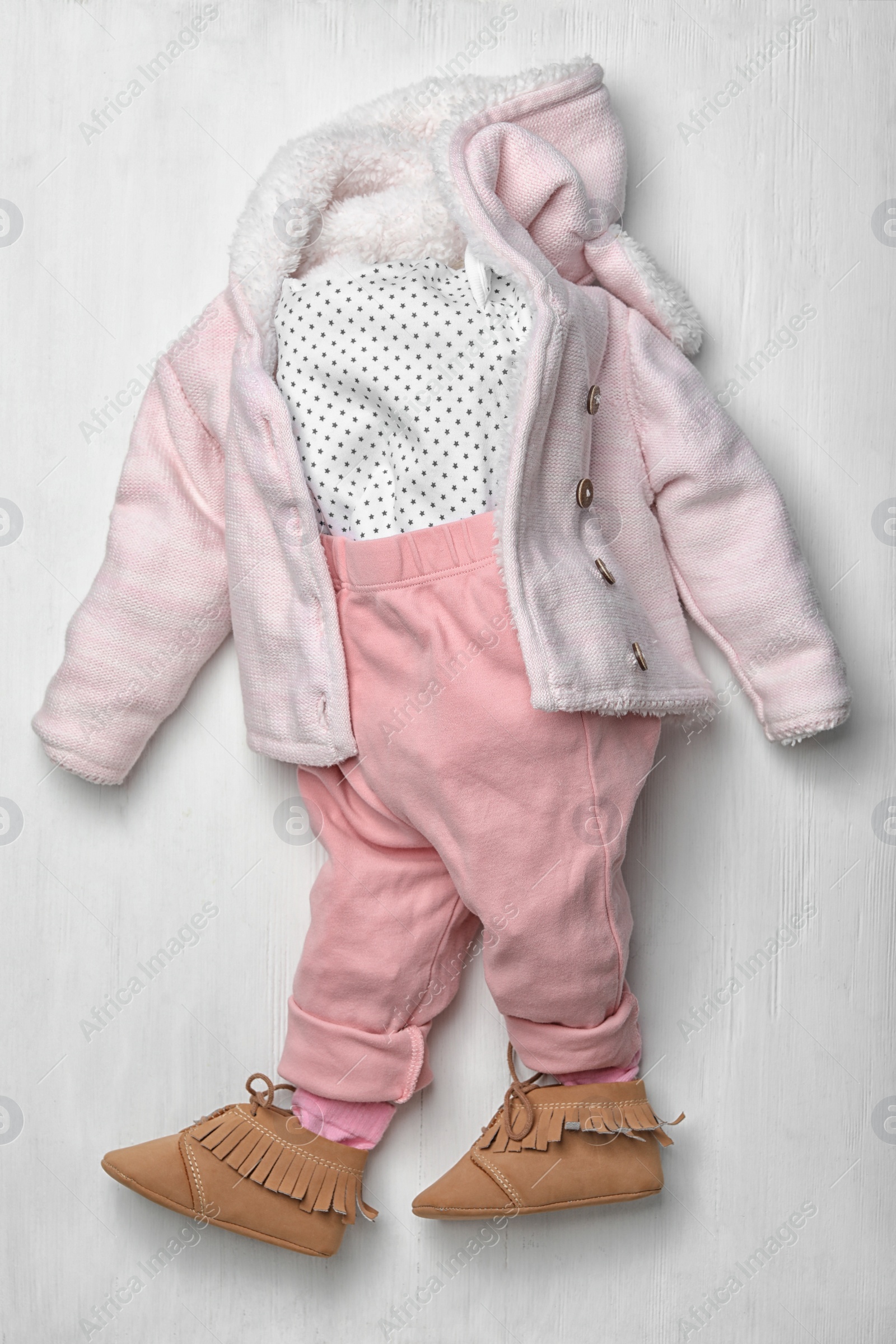 Photo of Child's clothes and booties on white wooden background, flat lay