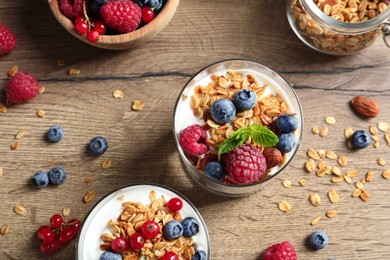 Image of Tasty dessert with yogurt, berries and granola on wooden table, flat lay