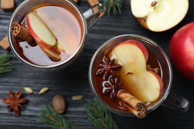 Photo of Aromatic hot mulled cider on black wooden table, flat lay