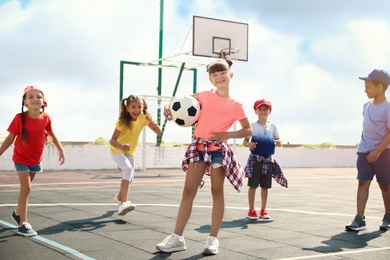 Photo of Cute children with soccer ball at sports court on sunny day. Summer camp
