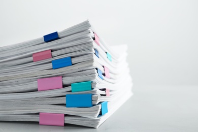 Photo of Stack of documents with binder clips on light table, closeup. Space for text