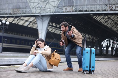 Being late. Worried couple with suitcase waiting at train station