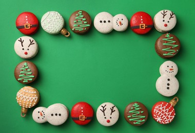 Photo of Frame of beautifully decorated Christmas macarons on green background, flat lay. Space for text