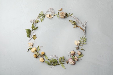 Photo of Dried flowers and leaves arranged in shape of wreath on light grey background, flat lay with space for text. Autumnal aesthetic