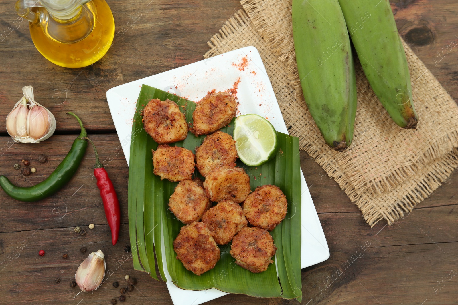 Photo of Delicious fried bananas, fresh fruits and different peppers on wooden table, flat lay