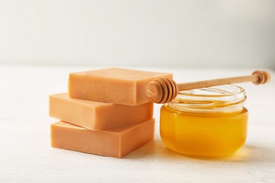 Handmade soap bars and jar of honey on white table