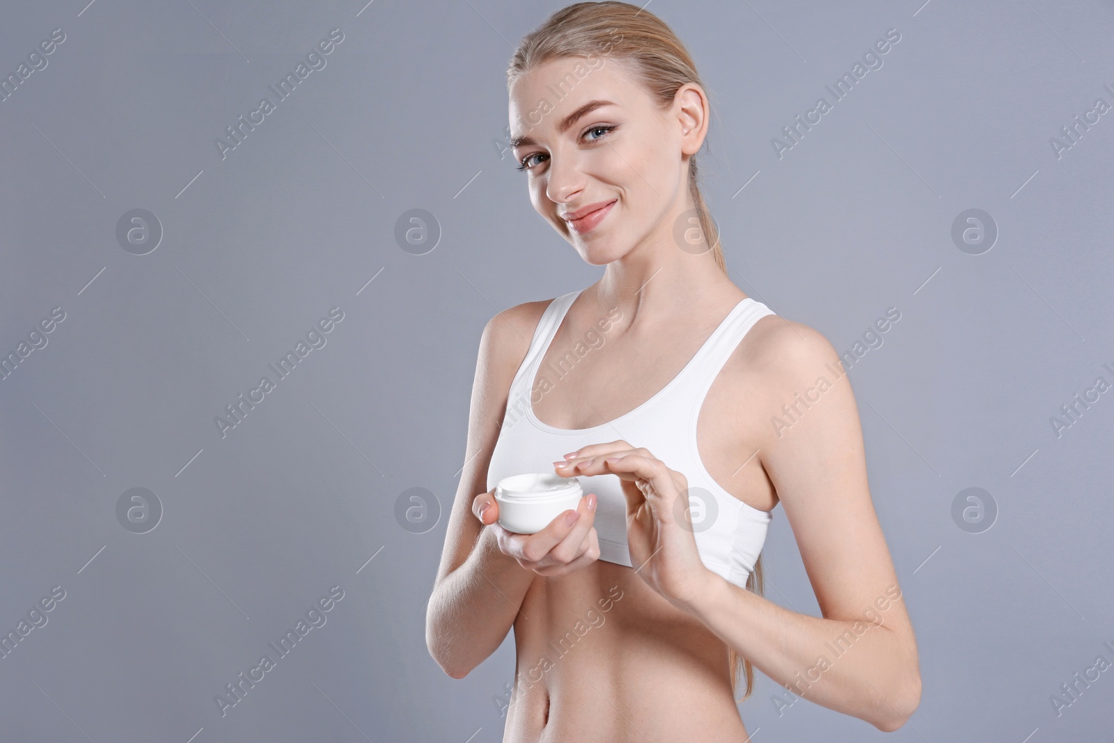 Photo of Young woman with jar of body cream on color background