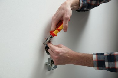 Photo of Electrician with pliers repairing power socket, closeup