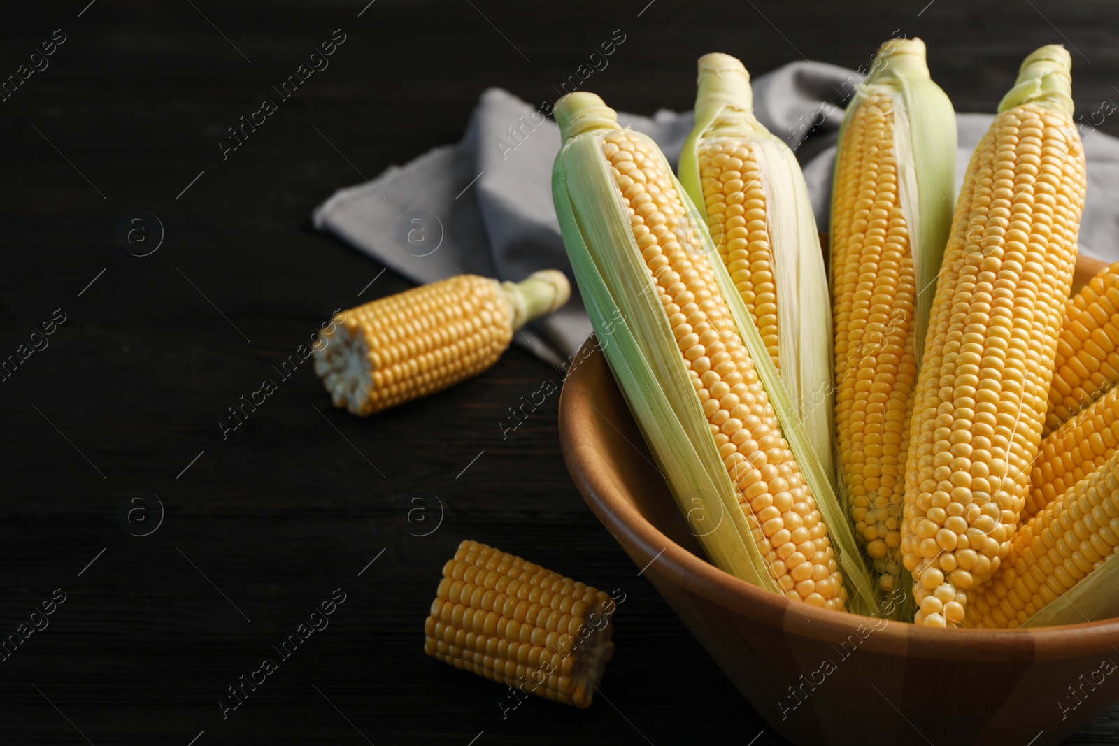 Photo of Bowl with tasty sweet corn cobs on table, closeup