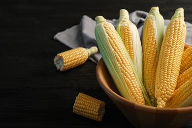 Photo of Bowl with tasty sweet corn cobs on table, closeup