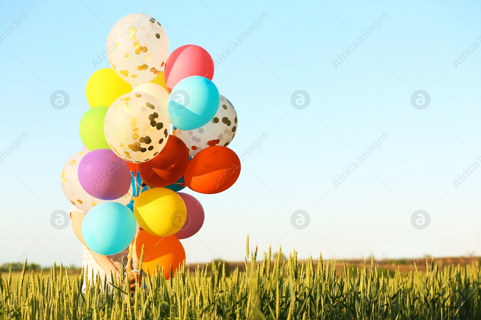 Photo of Young woman with colorful balloons in field on sunny day