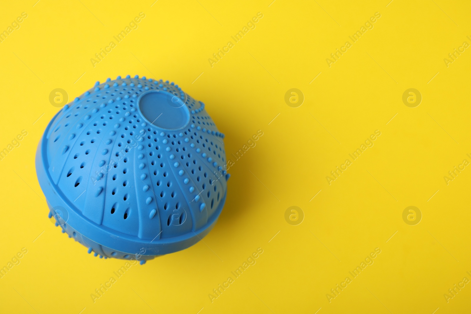 Photo of Laundry dryer ball on yellow background, top view. Space for text