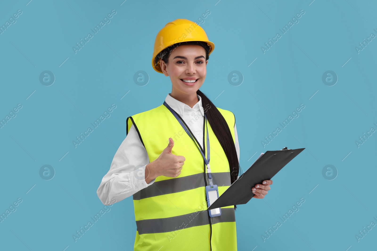 Photo of Engineer in hard hat showing thumb up on light blue background