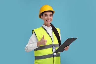 Engineer in hard hat showing thumb up on light blue background