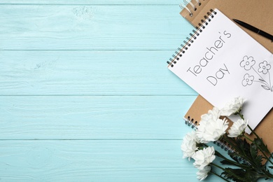 Photo of Flat lay composition with words TEACHER'S DAY on light blue wooden table. Space for text