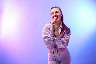 Emotional woman with microphone singing in color lights. Space for text
