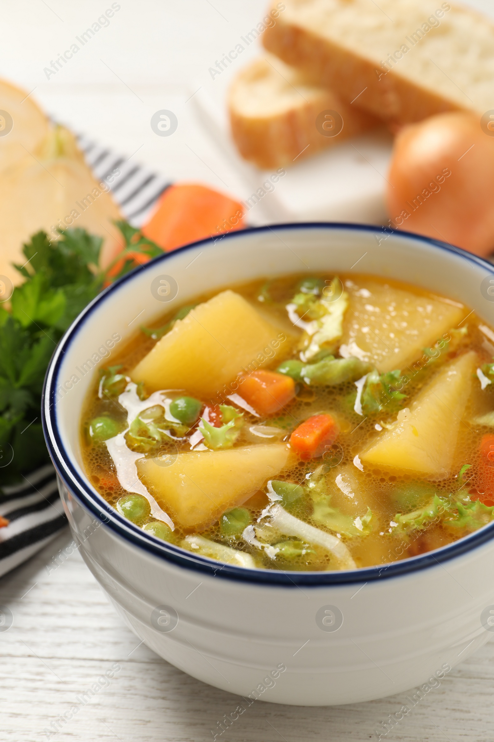 Photo of Bowl of delicious turnip soup on white wooden table, closeup