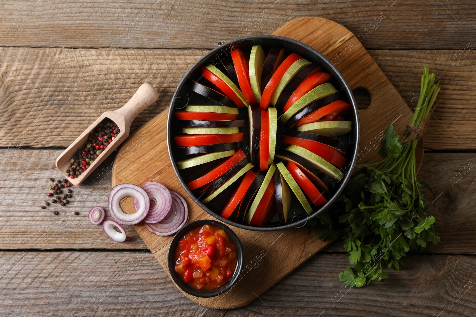 Photo of Cooking delicious ratatouille. Different fresh vegetables, scoop with spices and round baking pan on wooden table, flat lay