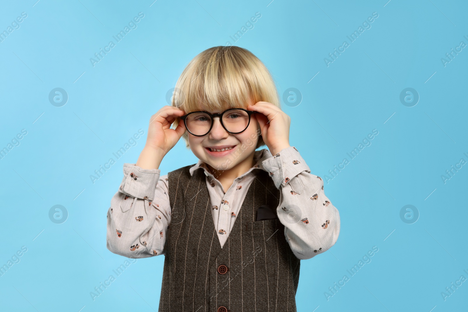 Photo of Cute little boy wearing glasses on light blue background