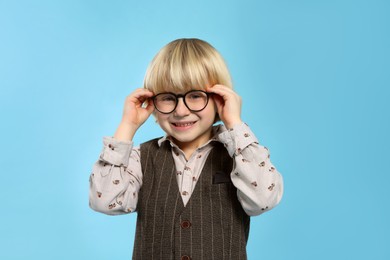 Photo of Cute little boy wearing glasses on light blue background