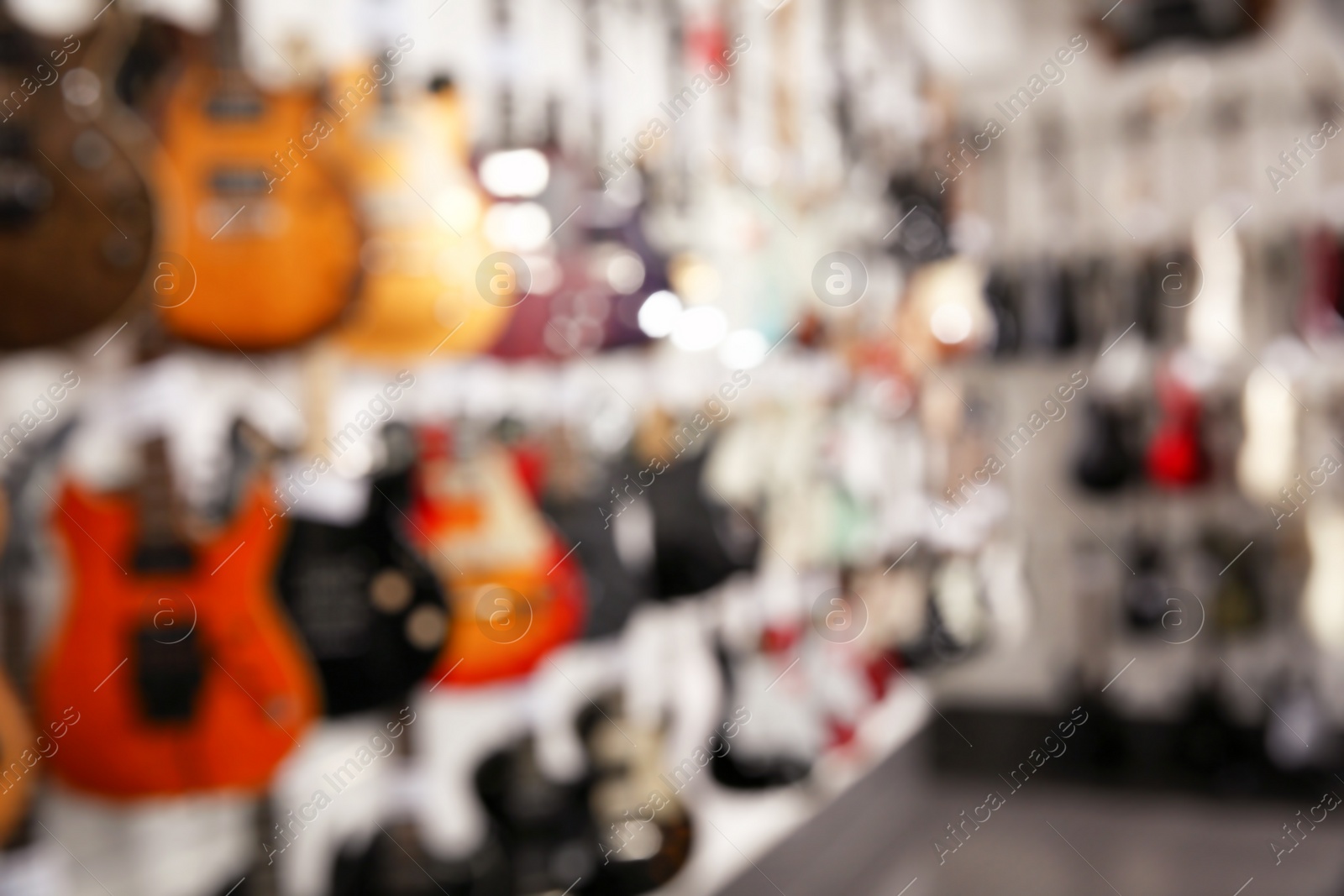 Photo of Rows of different guitars in music store, blurred view