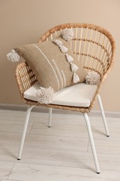 Photo of Stylish soft pillow on armchair near beige wall indoors