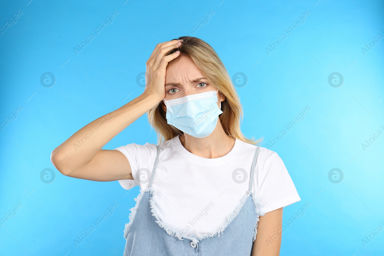 Photo of Stressed woman in protective mask on light blue background. Mental health problems during COVID-19 pandemic