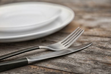 Photo of Empty dishware and cutlery on wooden table, close up view. Table setting