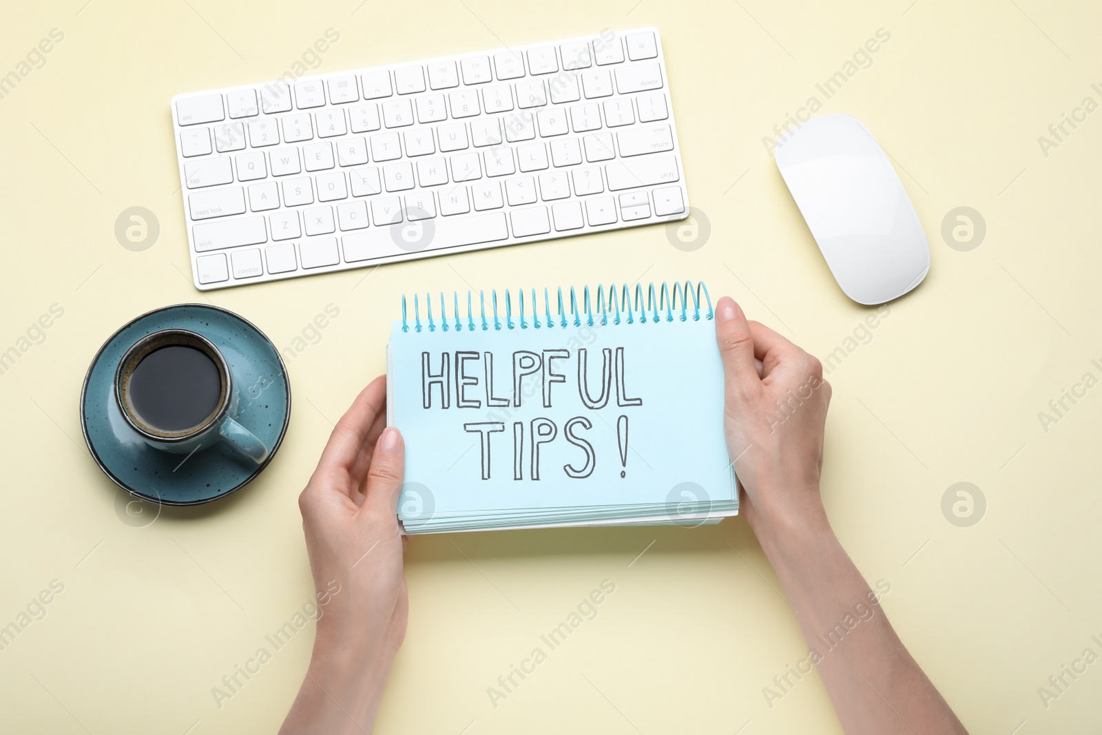 Photo of Woman holding notebook with phrase Helpful Tips at beige table, top view
