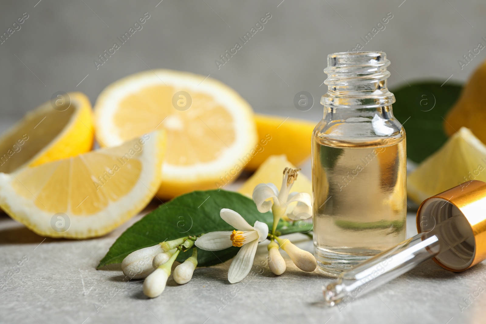 Photo of Citrus essential oil, flower and lemons on light table