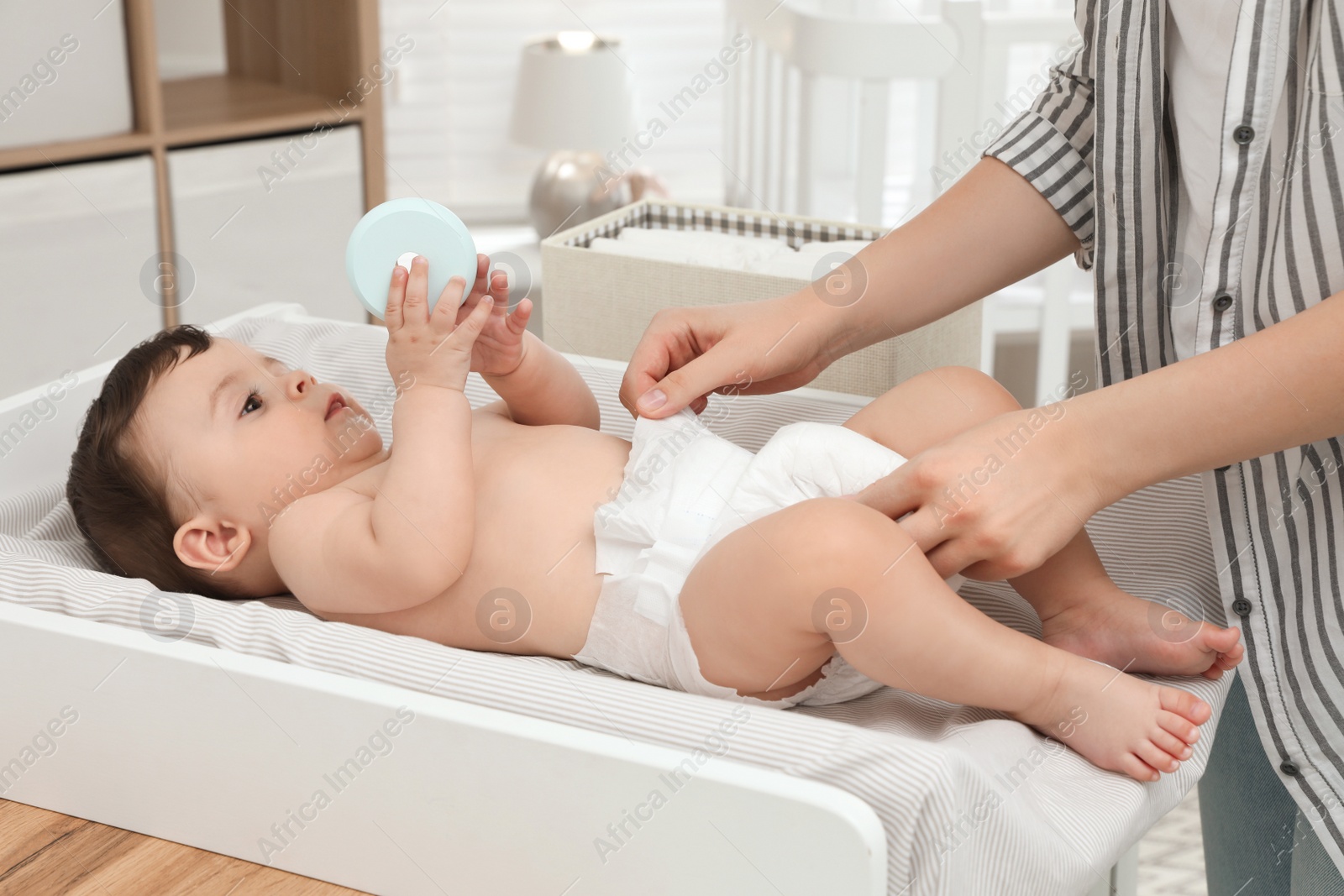 Photo of Mother changing baby's diaper on table at home, closeup