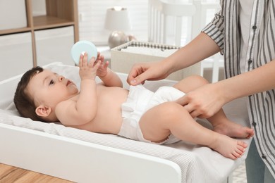 Mother changing baby's diaper on table at home, closeup