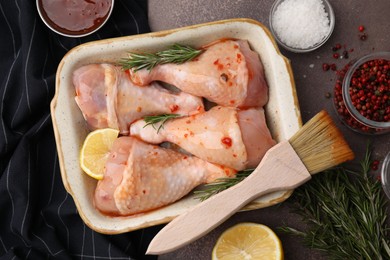 Photo of Flat lay composition with marinade and raw chicken drumsticks on brown table