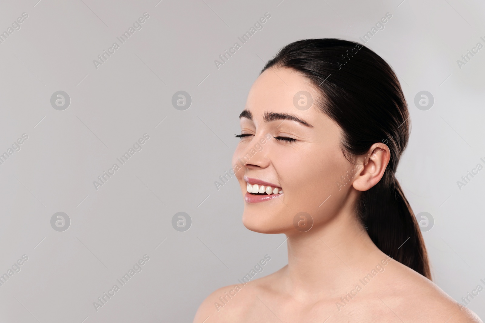 Photo of Portrait of attractive young woman with smooth skin on grey background. Space for text