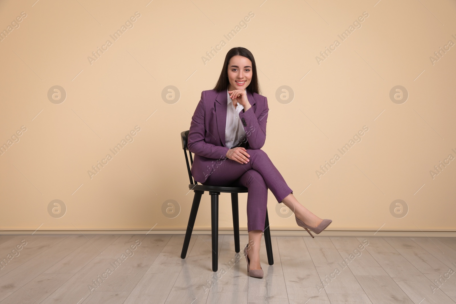 Photo of Young businesswoman sitting on chair near beige wall in office