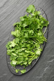 Photo of Fresh coriander on dark gray textured table, top view