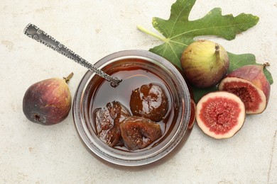 Jar of tasty sweet jam and fresh figs on white table, flat lay