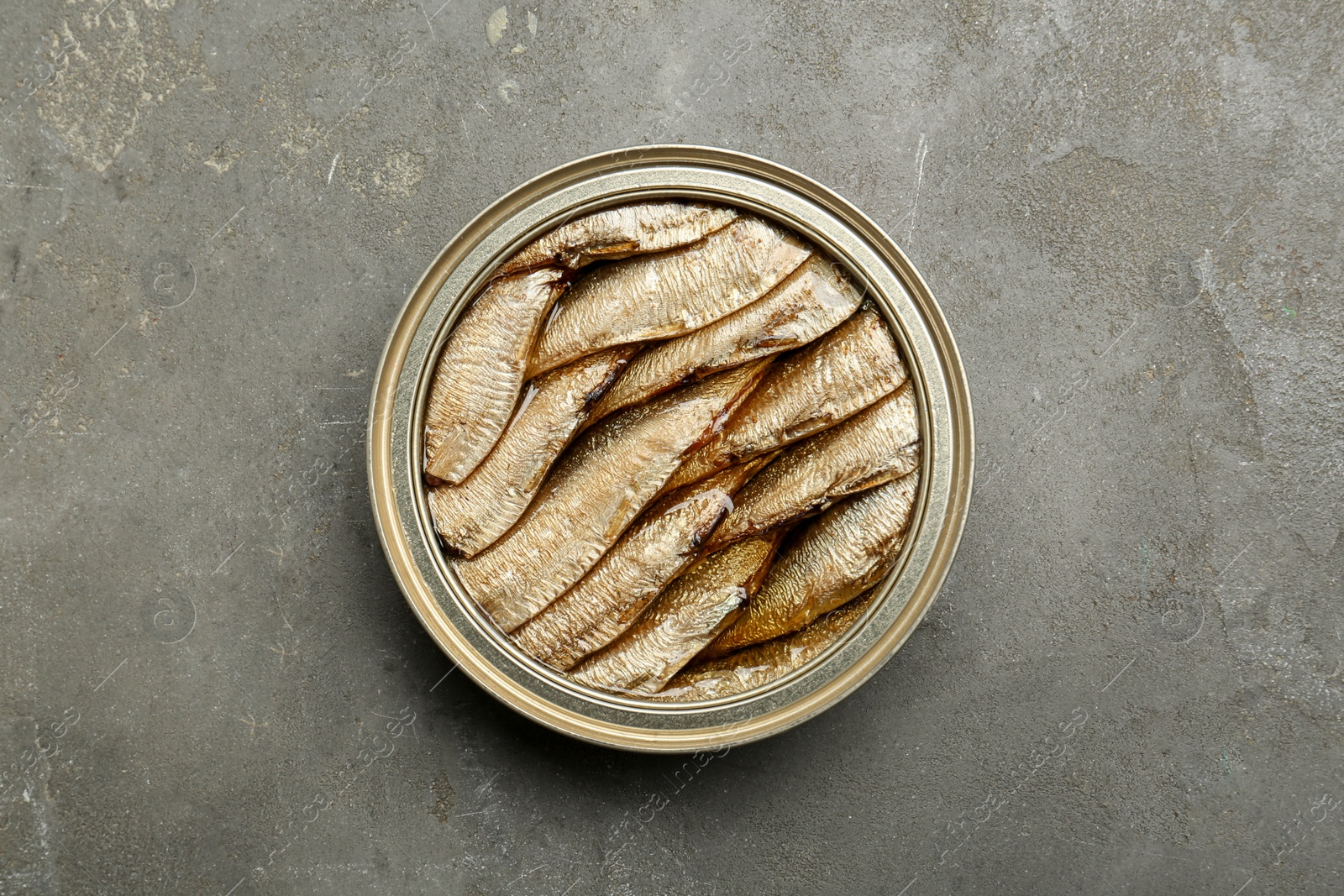 Photo of Sprats in tin can on grey textured table, top view