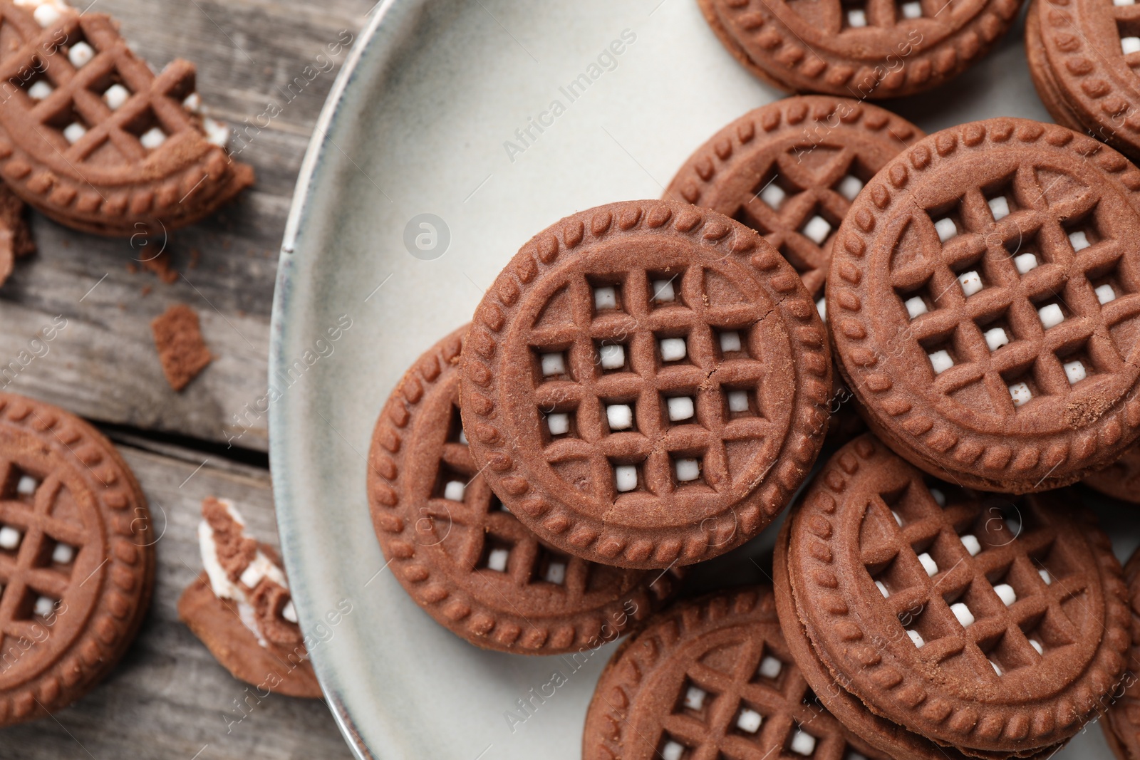 Photo of Tasty chocolate sandwich cookies with cream on wooden table, closeup