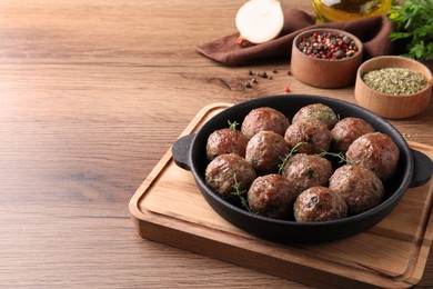 Photo of Tasty cooked meatballs served on wooden table. Space for text
